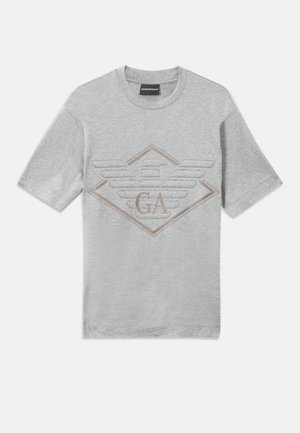 T-shirt gris à manches courtes en coton. Présente un logo en broderie en forme de diamant avec "GA" et des détails d'ailes en beige. Col rond.
