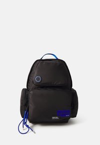 Black backpack made of nylon, featuring a rounded shape, a blue hanging cord, and a front pocket with a blue label and circular accent.