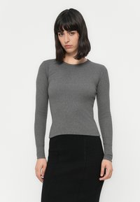 Gray long-sleeve fitted top in ribbed fabric, paired with a black skirt. The neckline is round with a smooth texture.