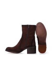 Brązowe zamszowe botki za kostkę z okrągłym noskiem, zamkiem błyskawicznym po boku oraz drewnianym, warstwowym obcasem. Podeszwa zewnętrzna ma teksturowany wzór dla lepszej przyczepności.