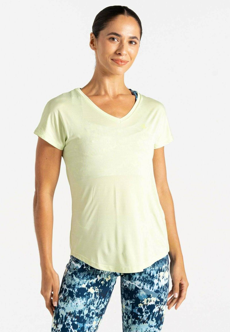 Camiseta amarilla claro de cuello en V con mangas cortas, combinada con leggins de patrón multicolor con manchas azules y blancas.