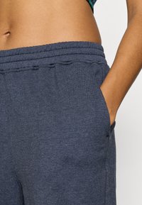 Σκούρες μπλε φόρμες με ελαστική μέση με κορδόνι, πλαϊνές τσέπες και απαλό, υφασμένο ύφασμα. Διαθέτουν άνετη εφαρμογή και ελάχιστες ραφές.