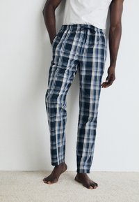 Pantalons de pyjama à carreaux bleu marine et blancs avec une taille élastique et un cordon de serrage. Tissu léger avec une coupe décontractée. Pas de poches.
