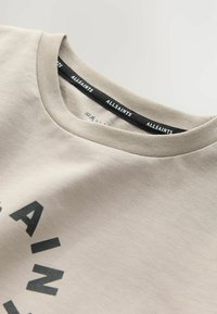 Beige Baumwoll-T-Shirt mit Rundhalsausschnitt und dunkelgrauem Textdesign. Verfügt über eine weiche Textur und ein Etikett mit "ALLSAINTS" in Schwarz bedruckt.