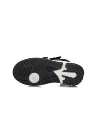 Schwarze und weiße Sneakersohle mit strukturiertem Profil, kreisförmigem Design in der Nähe der Ferse und teilweise sichtbaren Klettverschlüssen an der Seite.