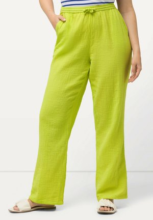 Limoengroene brede broek van textuurstof. Voorzien van een elastische tailleband met een trekkoord. Gepaald met lichtgekleurde sandalen.