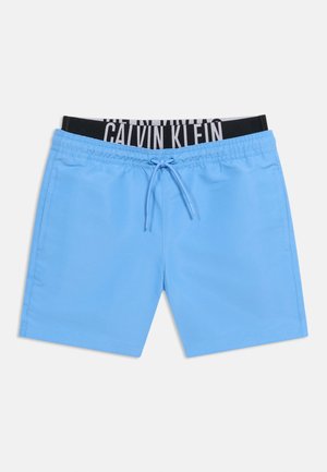 Pantaloni scurți de baie albastru deschis cu buzunare frontale și șnur reglabil, care dezvăluie o talie interioară neagră cu marca Calvin Klein.