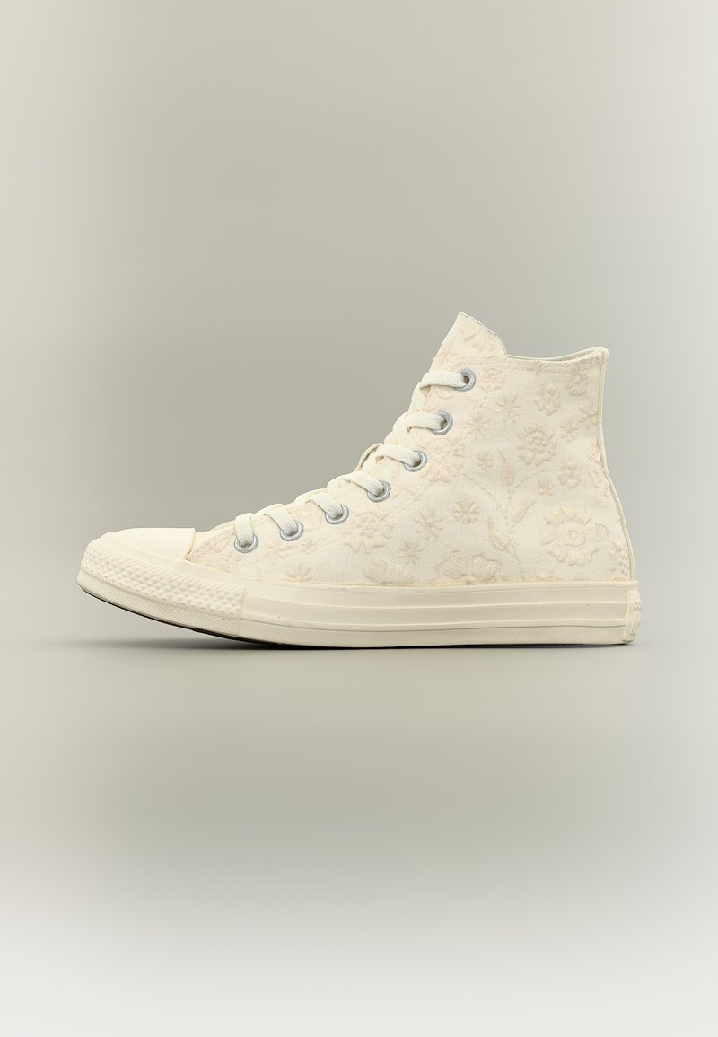High-Top-Sneaker in Creme mit geprägt-blumigen Mustern, weißer Gummisohle und Metallösen für die Schnürsenkel.
