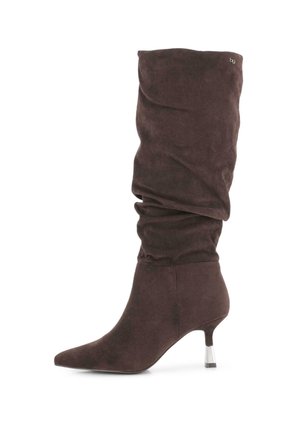 Bota alta hasta la rodilla de ante marrón oscuro, holgada, con puntera puntiaguda y tacón acrílico transparente, delgado y de altura media, sobre fondo blanco.