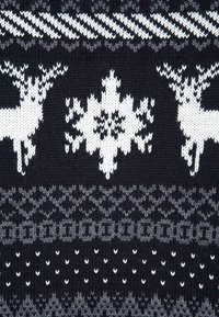 Gebreide trui met een zwarte achtergrond en witte en grijze geometrische patronen, waaronder ontwerpen van rendieren en sneeuwvlokken.