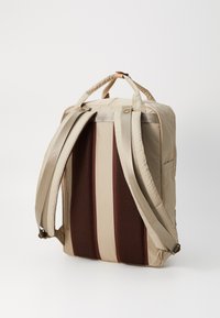 Beige backpack with textured, padded support, featuring mesh sections, wide straps, and leather accents for durability.