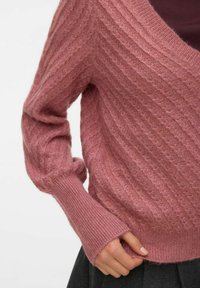 Roosa kudum, millel on V-kaelus, tekstureeritud soonikmustrit ja laiad varrukad. Kude näeb välja pehme ja kerge, ning sellel on ihule nauditav väikene talje.