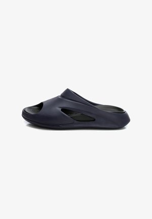 Zapato de casa de color navy con diseño de punta abierta, superficie texturizada y acentos recortados para ventilación. Material ligero y flexible.