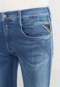 Jeans i ljusblå denim med lätt slitage. Har knappstängning, fem fickor och en märkesetikett på bakfickan.