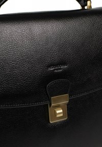 Zwarte leren aktetas met een gestructureerde afwerking, gouden metalen sluiting en een gegraveerd logo. Beschikt over een gestructureerde vorm en contrasterende stiksels.