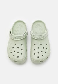 Zoccoli di colore verde chiaro realizzati in materiale sintetico stampato, dotati di fori di ventilazione, di una tracolla sul retro e di una soletta testurizzata per il comfort.