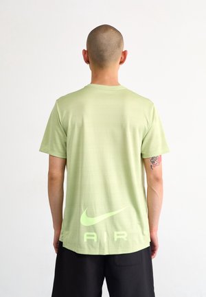 Camiseta Nike verde claro de manga corta, con una tela texturizada y un gran gráfico "AIR" en un tono ligeramente más oscuro en la parte trasera.