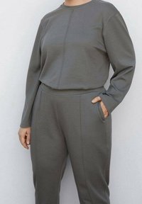 Ensemble deux pièces gris assorti en tissu doux, comprenant un haut à manches longues et un pantalon fuselé avec des poches latérales, avec des détails de coutures minimalistes.