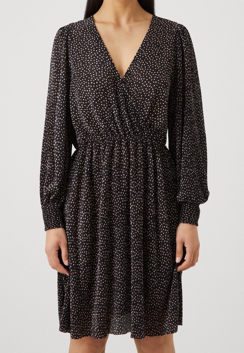 Schwarzes Kleid mit tiefem V-Ausschnitt, langen Ärmeln, geraffter Taille und verstreutem Muster aus weißen und hellbeigen Punkten. Weicher Stoff, fließendes Design.