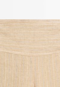 Tessuto di lino beige con sottili righe verticali blu e crema. Texture liscia, con una cintura sagomata e dettagli di cuciture ordinate.