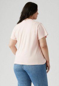 Camiseta de manga corta de color rosa claro con un ajuste relajado, textura suave y cuello redondo. Combinada con unos vaqueros de mezclilla azul.
