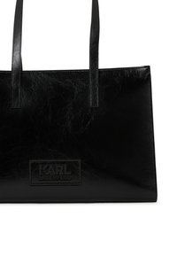 Sac cabas en cuir noir avec une texture lisse, doté de deux longues poignées et d'un logo 'KARL LAGERFELD' en relief à l'avant.
