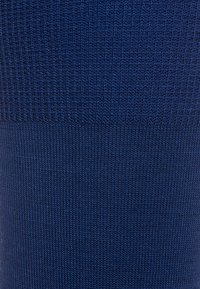 Tela de punto azul marino con un relieve texturizado y secciones lisas, creando una transición fluida entre diferentes patrones de tejido.