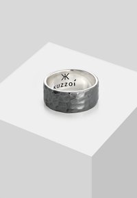 Anello in argento martellato con finitura grigio scuro e banda interna liscia. Presenta il logo inciso "Kuzzoi" all'interno.
