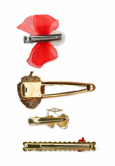 Quatre barrettes métalliques décoratives, dont une avec un nœud en tissu rouge, disposées verticalement sur un fond blanc.