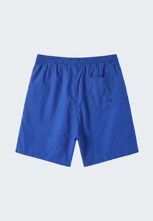 Costume da uomo blu con vita elastica e tasca posteriore singola con piccolo foro di drenaggio su sfondo chiaro.