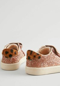 Glitzernde rosa Turnschuhe mit glatter Textur, die mit braunem und schwarzem Leopardenfell-Akzenten an der Ferse und beigen Gummisohlen ausgestattet sind.