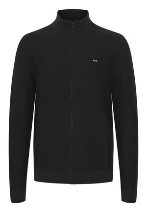 Svart zip-up cardigan med en teksturert ribbestruktur, høy krage og liten logo med røde, hvite og blå detaljer på brystet.