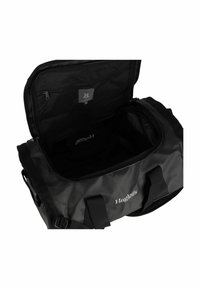 Zwarte sporttas met een ruime binnenkant, glad nylon materiaal, dubbele draaghandvatten en een ritssluiting. Het merclogo is zichtbaar aan de binnenkant.