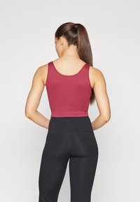 Burgunderfarget ribbestrikket crop top med brede stropper og en tettsittende design, kombinert med høyt liv sorte leggings med en glatt og elastisk tekstur.