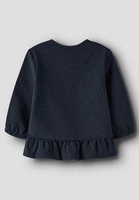 Top de manga larga azul marino con cuello redondo, con un dobladillo con volantes y un pequeño patrón de puntos dorados en toda la prenda. Tejido suave con ligera textura.