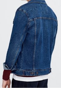 Jeansowa kurtka w ciemnoniebieskim kolorze o klasycznym kroju. Posiada kołnierz, guziki oraz przeszycia na plecach i rękawach.