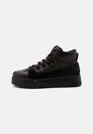 Baskets montantes en cuir noir et suède avec semelle épaisse et lacets brun foncé, vue de profil sur fond clair uni.