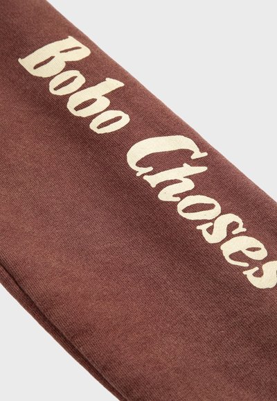 Tela marrón con texto en color blanco roto que dice "Bobo Choses" en una fuente audaz y estilizada.