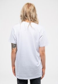 White cotton T-shirt with short sleeves, relaxed fit, and a round neckline. The back features minimal design with a smooth texture.
