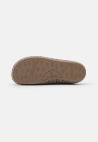 Semelle en caoutchouc avec motifs de grip texturés, couleur marron clair, et tige douce et duveteuse dans un design beige et gris tacheté.