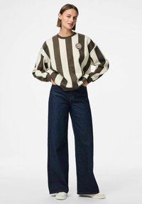 Felpa a righe marroni e crema con scollo rotondo e dettaglio del logo, abbinata a pantaloni a gamba larga in denim scuro a vita alta.