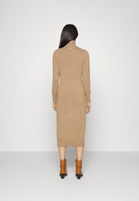 Strick-Midi-Kleid in Camel-Farbe, mit Rollkragen, langen Ärmeln und gerippten Bündchen, kombiniert mit braunen Knöchelstiefeln.