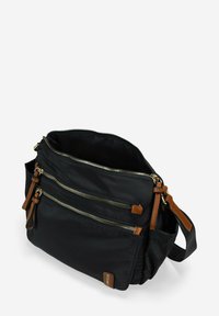 Bolsa negra de nailon con tres bolsillos frontales con cremallera, detalles en cuero marrón, correa de hombro ajustable y un compartimento principal espacioso.