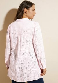 Camicia a maniche lunghe rosa chiaro con motivo di ricamo floreale, colletto e vestibilità morbida con schiena leggermente più lunga.