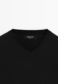 Czarny sweter z dekoltem w serek, wykonany z miękkiego materiału, z ryflowanym wykończeniem dekoltu oraz metką z napisem "Massimo Dutti" wewnątrz.