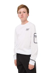 T-shirt bianco a maniche lunghe con la scritta "NEVER LOOK BACK" stampata sul petto, dettagli grigi sulle maniche e polsini a coste. Indossato con pantaloni neri.