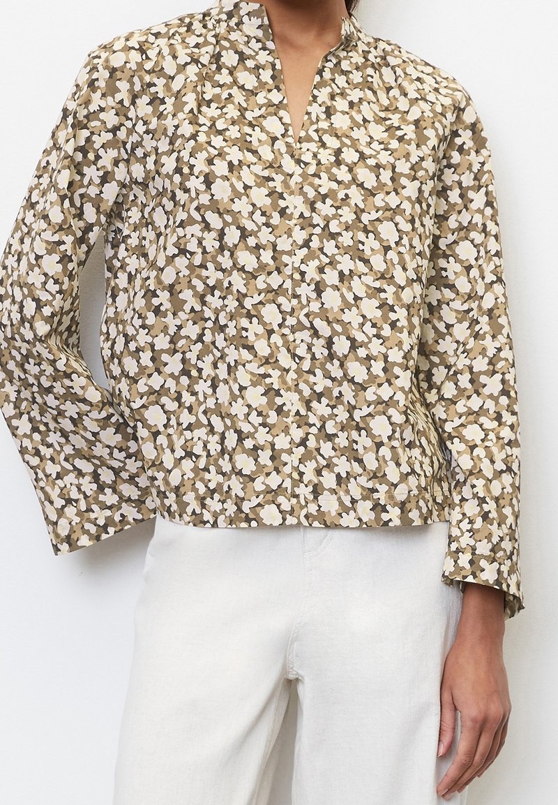 Blouse à motif floral en marron et crème avec un col mandarin et des manches longues, fabriquée en tissu léger avec une finition légèrement texturée.