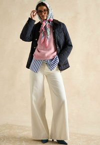 Navy'owa kurtka pikowana, jasnoróżowy sweter, niebieska i biała bluzka w paski pod spodem, szerokie białe spodnie, szal w kwiatowy wzór, turkusowe szpilki.