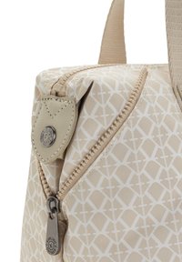 Beige taske med geometrisk mønster, udstyret med lynlås og en læderdetalje med en cirkulær metal logo. Tekstureret stofmateriale.