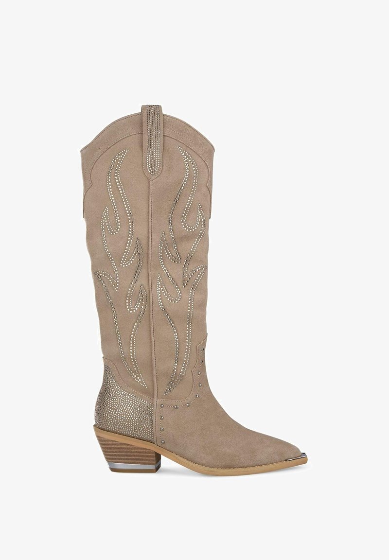 Bota vaquera de ante color canela con costuras decorativas, punta puntiaguda y tachuelas metálicas. Tacón ancho con superficie texturizada y detalles estampados.